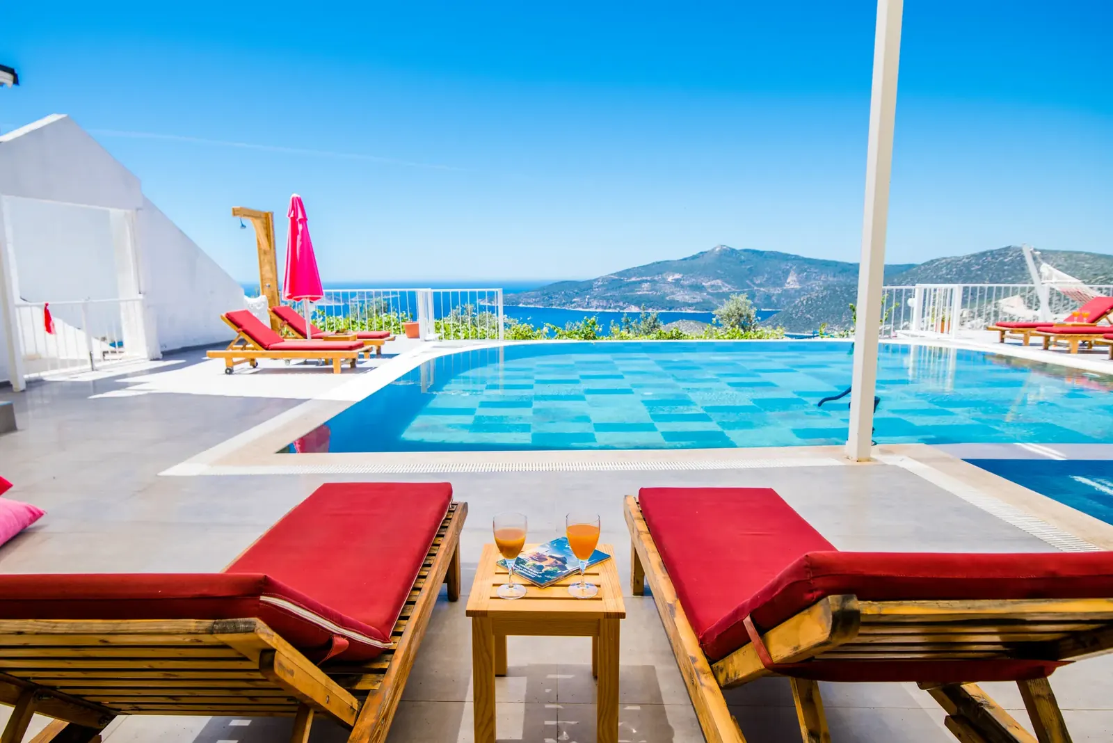 Red sun loungers by the infinity pool at Deneme Villa Kaş overlooking the sea